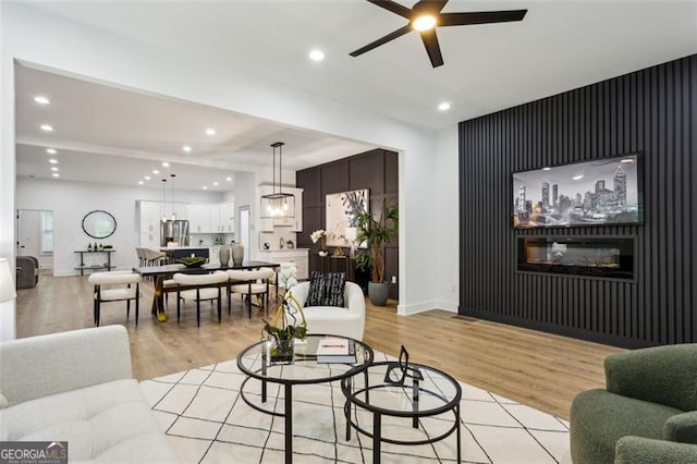 living room with recessed lighting, a ceiling fan, an accent wall, and light wood-type flooring