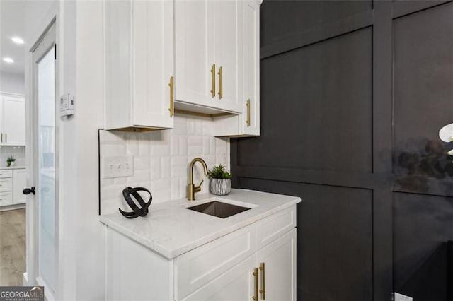 bar featuring a sink, decorative backsplash, light wood-type flooring, and recessed lighting