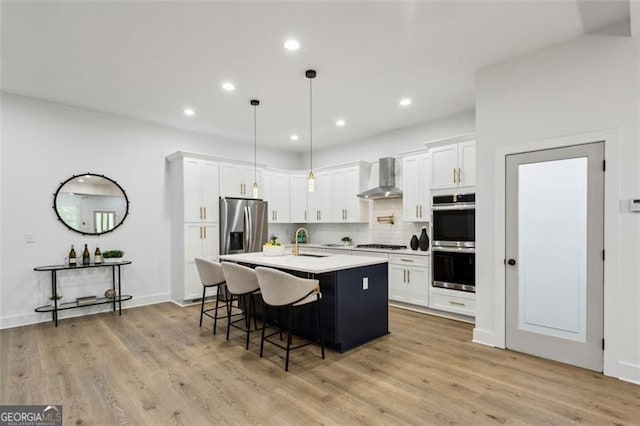 kitchen featuring wall chimney range hood, decorative backsplash, a sink, a breakfast bar, and stainless steel appliances