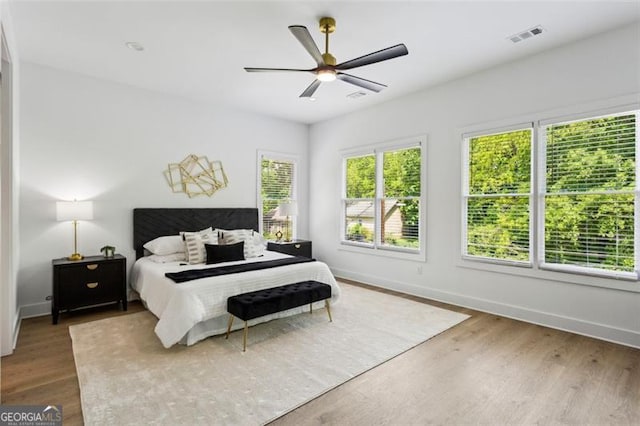 bedroom featuring baseboards, ceiling fan, wood finished floors, and visible vents