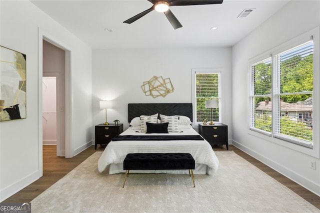 bedroom featuring visible vents, baseboards, ceiling fan, and wood finished floors