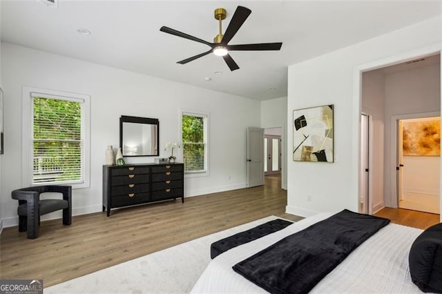 bedroom with baseboards, multiple windows, and wood finished floors