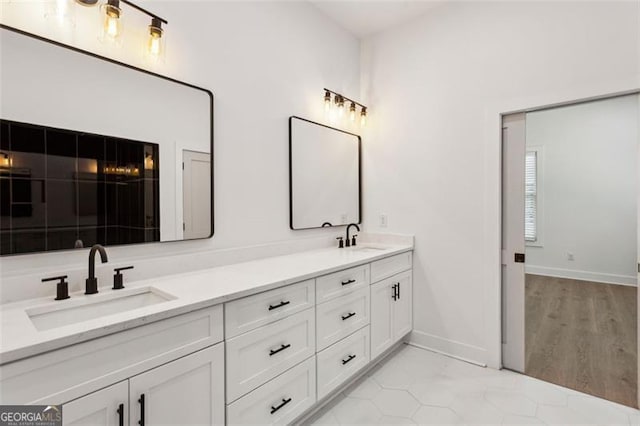 bathroom featuring double vanity, a sink, and baseboards