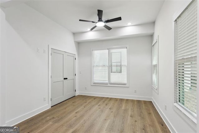 unfurnished bedroom with recessed lighting, baseboards, wood finished floors, and multiple windows