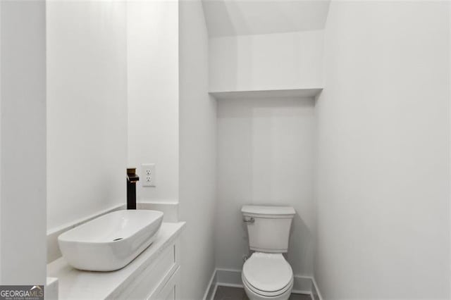 bathroom featuring baseboards, toilet, and vanity