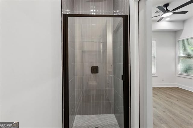 bathroom featuring a ceiling fan, baseboards, a shower stall, and wood finished floors