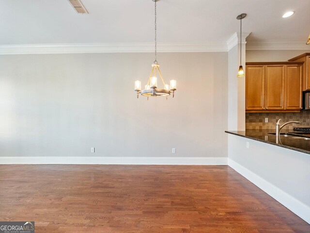unfurnished dining area with visible vents, crown molding, wood finished floors, a sink, and a notable chandelier