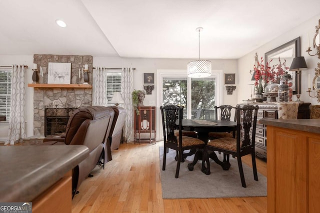 dining area with a stone fireplace and light wood-style flooring