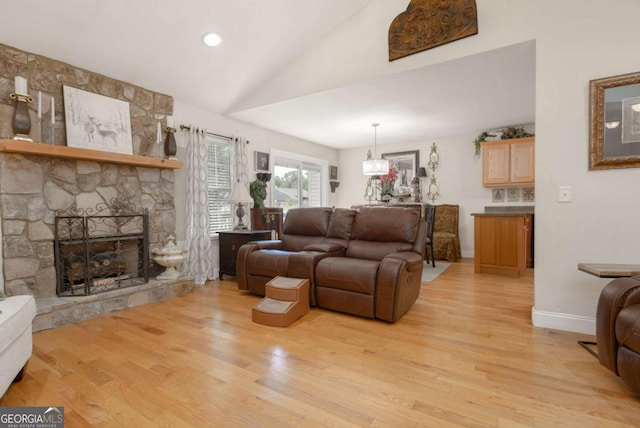 living area featuring a stone fireplace, light wood-style flooring, baseboards, and vaulted ceiling