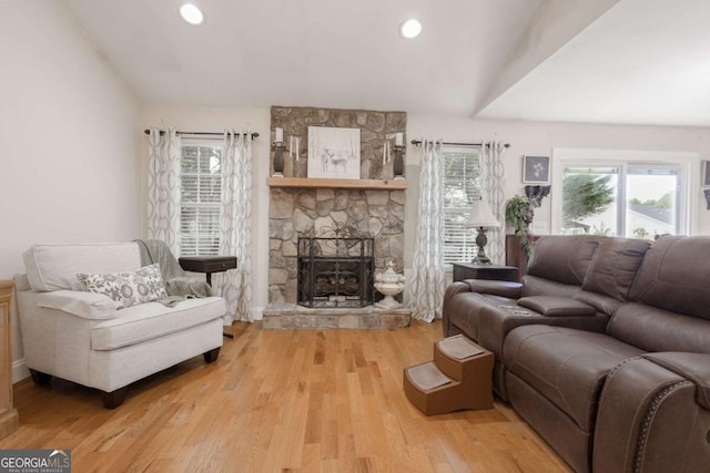 living room with a stone fireplace, recessed lighting, wood finished floors, and lofted ceiling