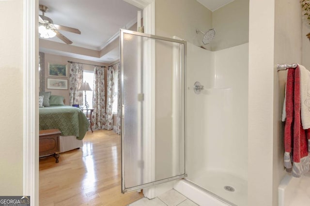 bathroom featuring a ceiling fan, wood finished floors, ensuite bathroom, ornamental molding, and a stall shower