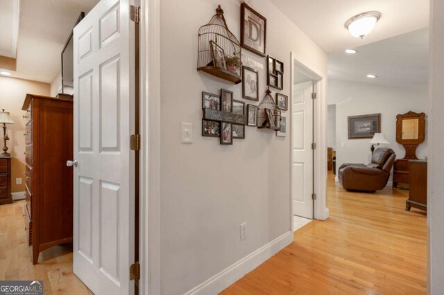 hallway featuring recessed lighting, baseboards, vaulted ceiling, and light wood-style flooring