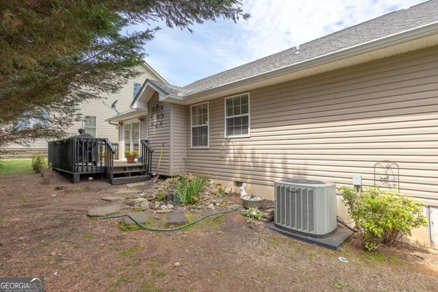 view of side of home with central air condition unit and a wooden deck