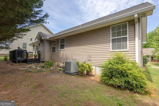 view of property exterior with central air condition unit, a wooden deck, and a yard