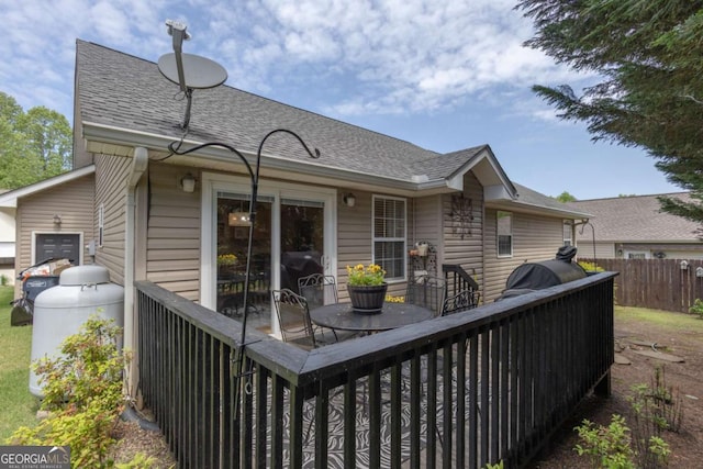 rear view of house featuring roof with shingles and fence