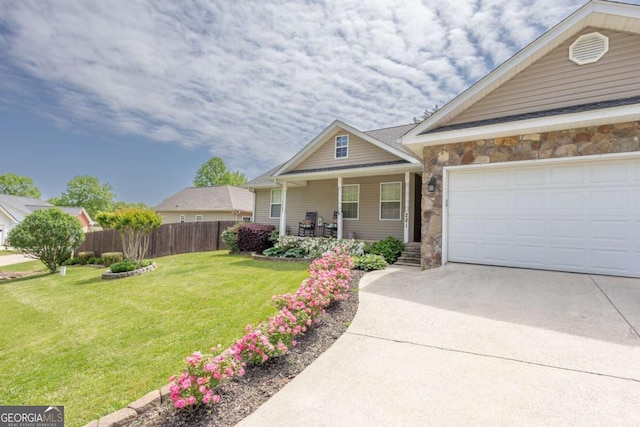 view of front of property with fence, a front lawn, stone siding, covered porch, and driveway