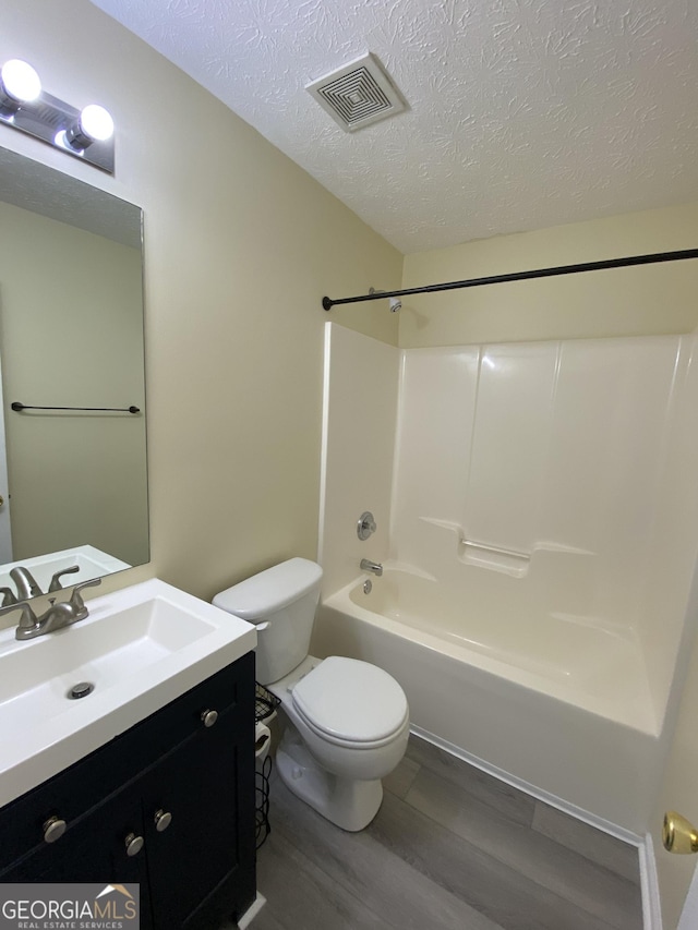 253 Whistle Way, Locust Grove, GA 30248 - full bath featuring wood finished floors, toilet, a textured ceiling, vanity, and  shower combination
