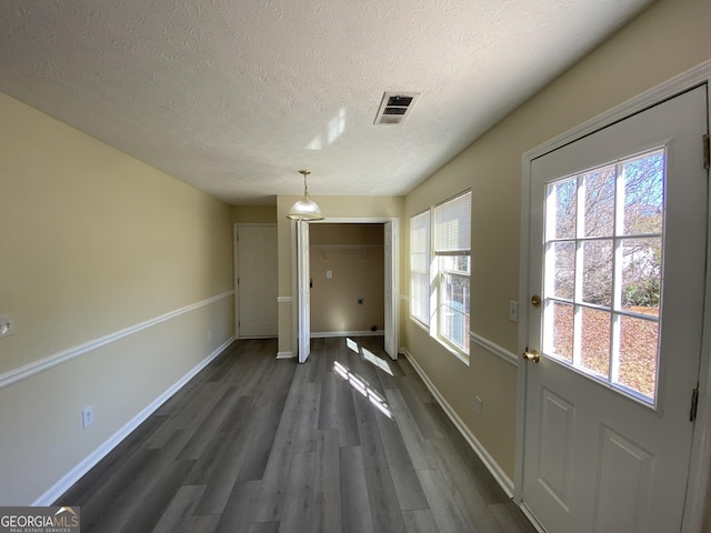 doorway with baseboards, visible vents, a textured ceiling, and dark wood-type flooring