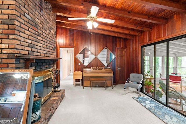 sitting room with a brick fireplace, ceiling fan, wooden walls, and wooden ceiling