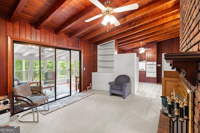 living area featuring a ceiling fan, wood walls, and wooden ceiling