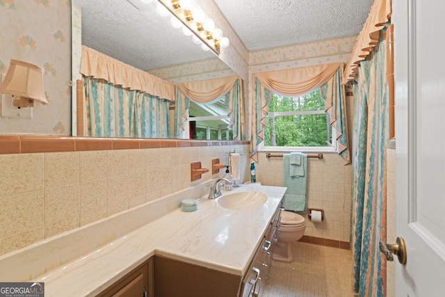 bathroom with wallpapered walls, a textured ceiling, toilet, and tile walls