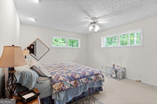 bedroom with carpet flooring, a textured ceiling, baseboards, and multiple windows