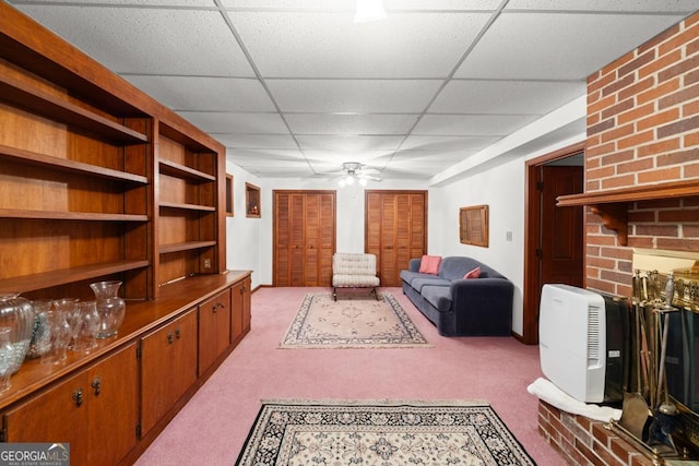 living area with a ceiling fan, carpet flooring, and a paneled ceiling