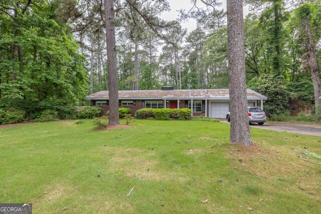 ranch-style house featuring an attached garage, a front lawn, driveway, and brick siding