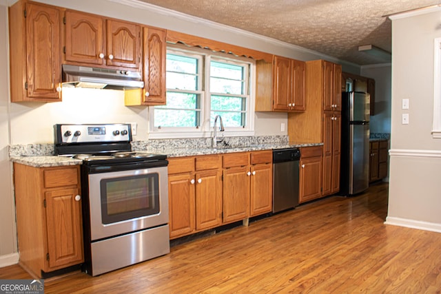 6470 Sherwood Trl, Austell, GA 30168 - kitchen with stainless steel appliances, under cabinet range hood, ornamental molding, light wood finished floors, and brown cabinetry
