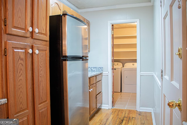 laundry area with washer and dryer, laundry area, crown molding, and light wood-style floors