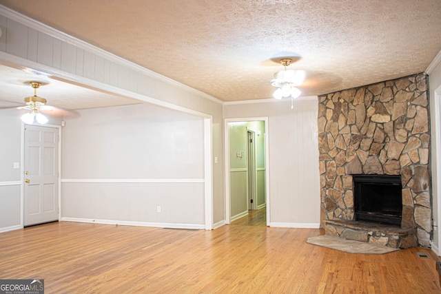 unfurnished living room featuring a stone fireplace, ceiling fan, and wood finished floors
