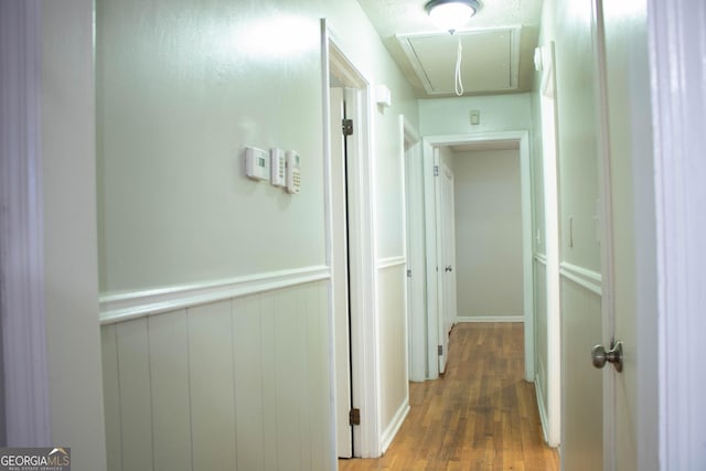hallway with attic access and wood finished floors