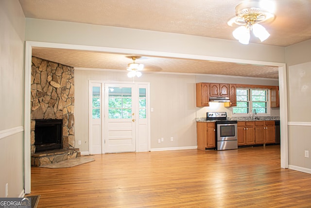 kitchen featuring brown cabinetry, stainless steel range with electric stovetop, ceiling fan, and light wood-style floors
