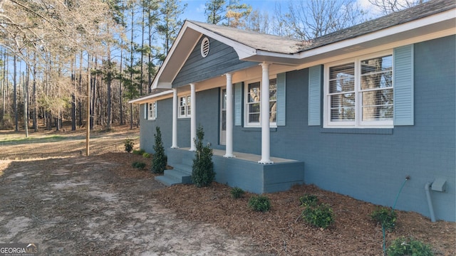 view of side of home featuring a porch and brick siding