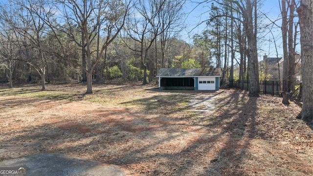 view of yard with a garage, fence, an outbuilding, and a wooded view