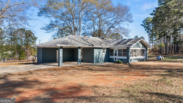 view of front of home featuring a sunroom, an attached carport, and driveway