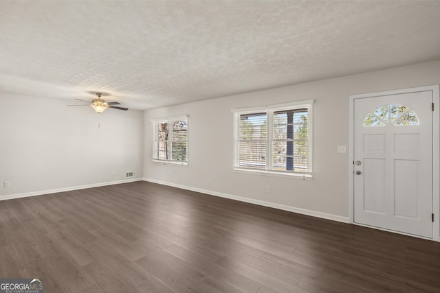 foyer featuring ceiling fan, a textured ceiling, dark wood finished floors, baseboards, and visible vents