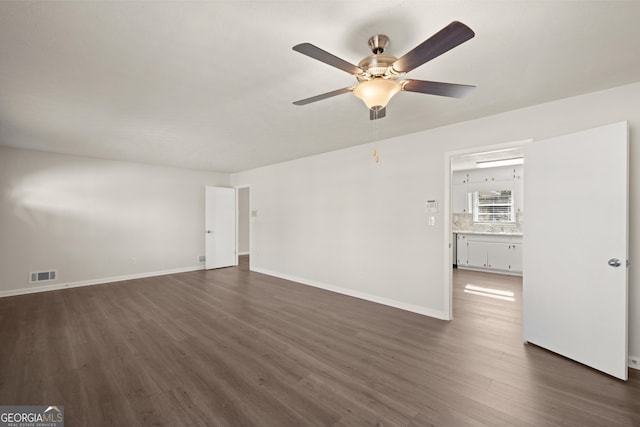 unfurnished living room featuring baseboards, a ceiling fan, dark wood-type flooring, and visible vents