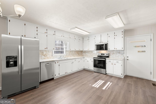kitchen with a sink, light wood-style flooring, white cabinets, and stainless steel appliances