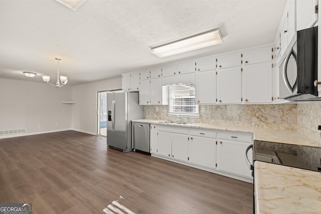 kitchen with visible vents, white cabinetry, backsplash, and stainless steel appliances