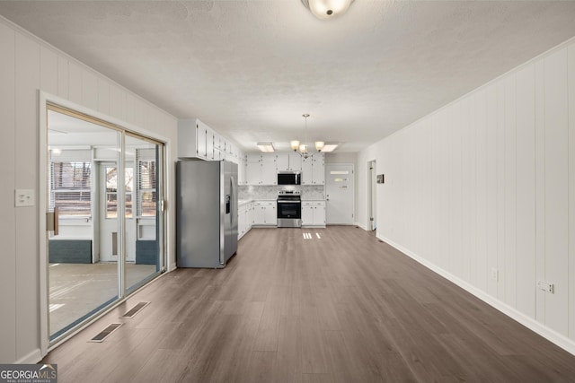 unfurnished living room with visible vents, baseboards, a notable chandelier, and dark wood-style floors
