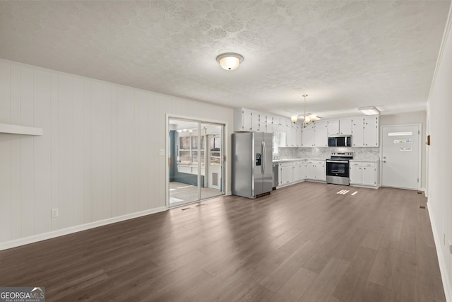 unfurnished living room featuring baseboards, dark wood-style floors, a textured ceiling, and a notable chandelier