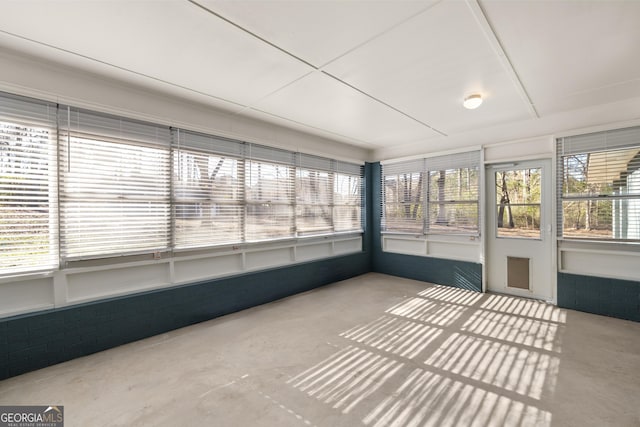 unfurnished sunroom featuring concrete floors and a wealth of natural light