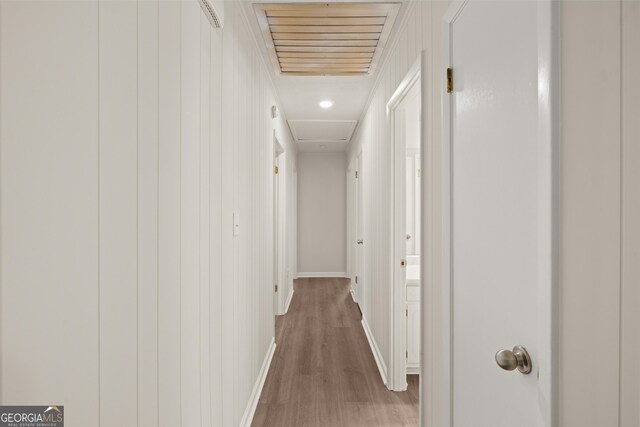 hall with baseboards, wood finished floors, and visible vents