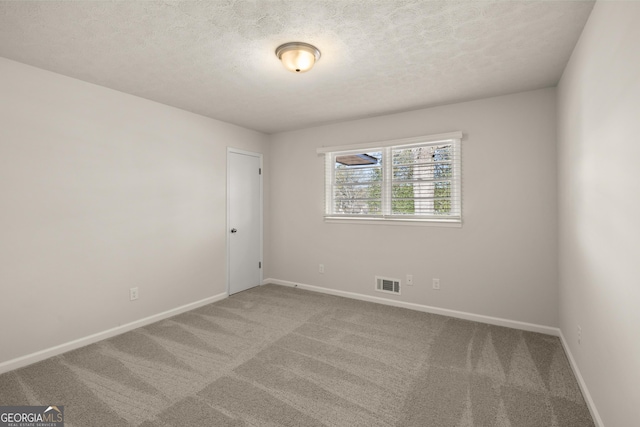carpeted spare room featuring visible vents, a textured ceiling, and baseboards