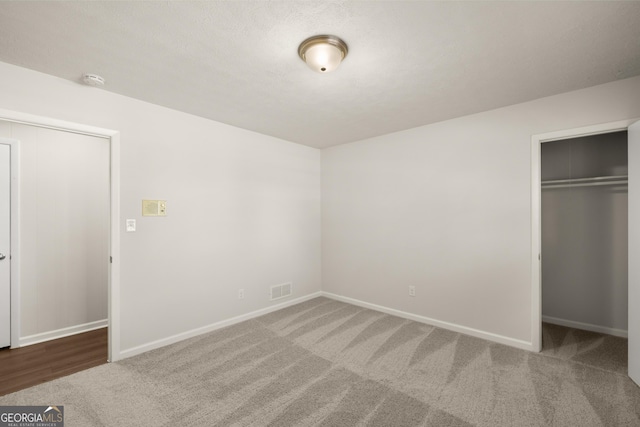 unfurnished bedroom with carpet floors, baseboards, visible vents, and a spacious closet
