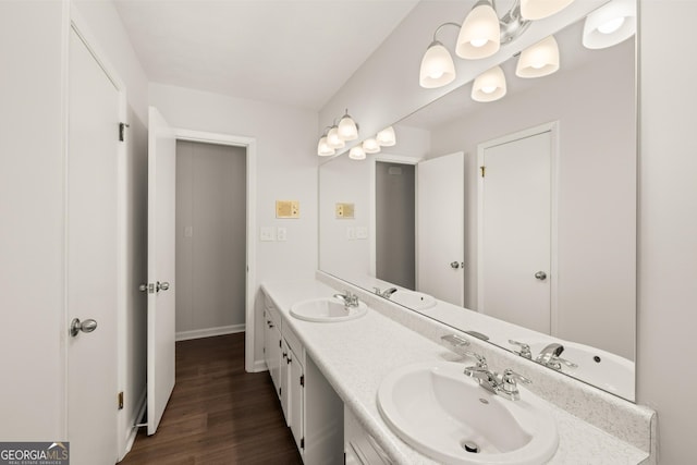 bathroom featuring double vanity, baseboards, a sink, and wood finished floors