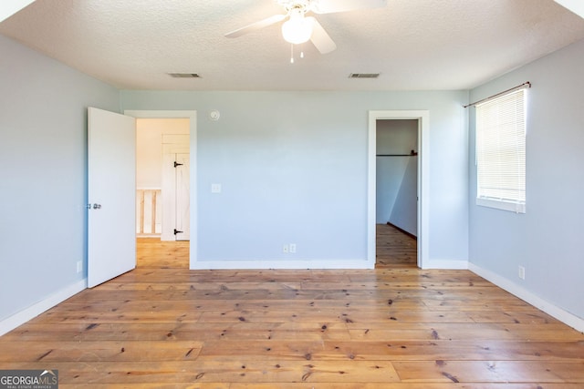 unfurnished bedroom featuring visible vents, a textured ceiling, baseboards, and hardwood / wood-style flooring