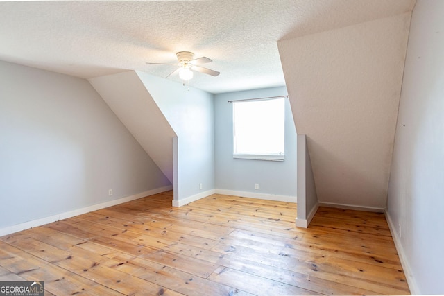 bonus room with a textured ceiling, ceiling fan, and light wood-style flooring