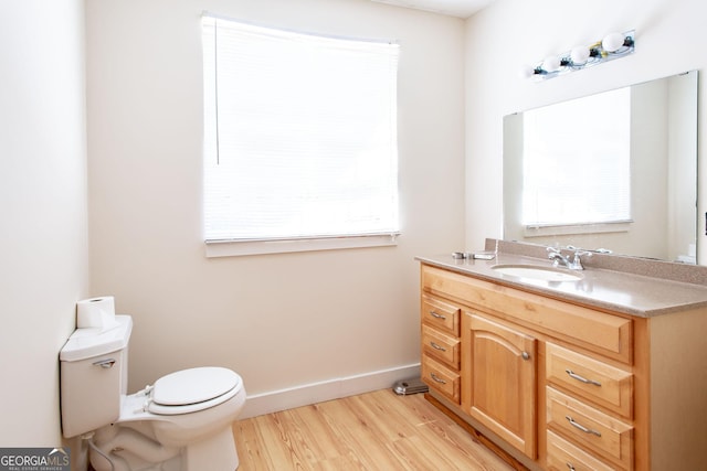 half bathroom with toilet, wood finished floors, and a wealth of natural light